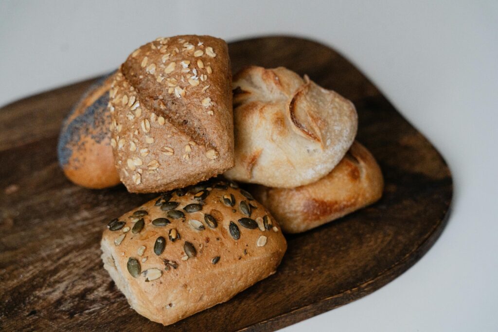 A selection of artisanal bread rolls with seeds, displayed on a rustic wooden board.